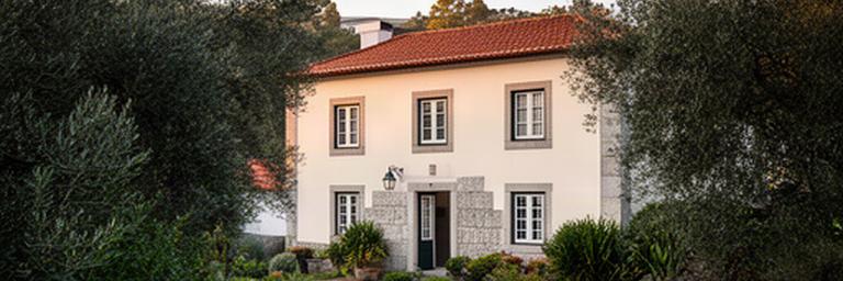 Fachada de uma casa de alojamento local na zona rural de Arganil, rodeada por vegetação da região de Coimbra