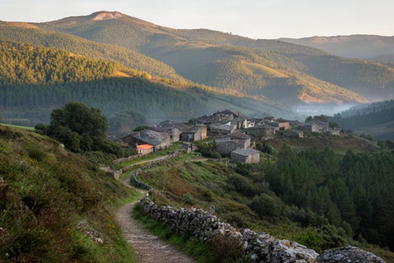 Encostas verdes da Serra do Açor junto a aldeia de xisto e trilho pedestre